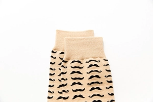 Detail of beige cotton blend socks with black mustache pattern and ribbed cuffs