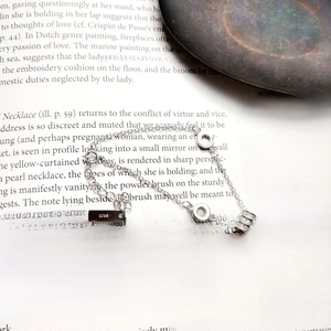 Detail of S925 sterling silver beaded bracelet with diamond-set cylinder on art book