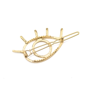 Minimalist evil eye hair clip in polished gold metal with a sleek geometric design