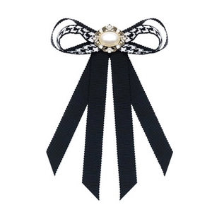 Macro detail of bow brooch showing houndstooth ribbon, large pearl and sparkling rhinestones