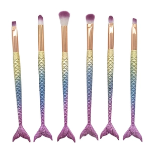 Detail of mermaid tail makeup brushes with gradient glitter handles and purple fiber tips