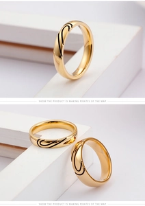 Close-up of golden titanium steel couple rings with black wave engraved patterns