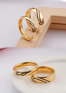 Close-up of gold heart-shaped pair rings for couples with black engraved curved patterns