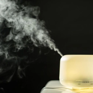 Ultrasonic aroma diffuser with warm light and mist, timing mode on dark background