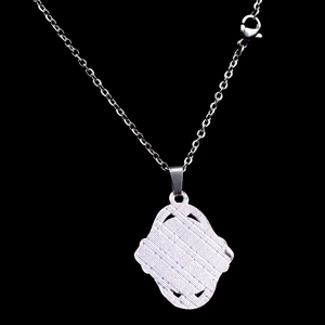 Détails de l'envers texturé du pendentif argenté et du fermoir mousqueton du collier
