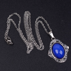 Gros plan d'un pendentif ovale vintage avec pierre bleue et gravure argentée