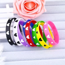 Close-up of colorful silicone heart bracelets in eight vibrant colors on a jewelry tray