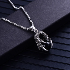 Détail d'un pendentif griffe de dragon en acier avec perle noire sur une chaîne argentée