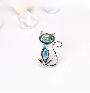 Detail view of a cat-shaped silver brooch with iridescent shell inlay and sparkling stones