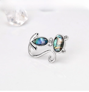 Macro shot of silver cat brooch with natural abalone shell inlay and rhinestone details