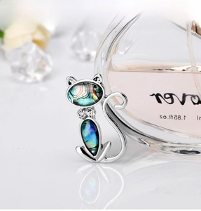 Detail showing an elegant silver cat brooch with iridescent shell inlay and tiny rhinestones