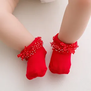 Close-up of red baby socks with white polka dot lace trim and cute red bows