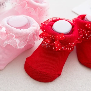 Close-up of cotton baby socks with layered lace trim, polka dots, and cute bows