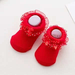 Detailed close-up of red infant socks with lace frills and white polka dot bow accents