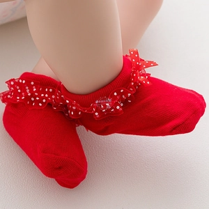 Close-up of red baby socks with layered lace ruffles and a satin ribbon bow detail