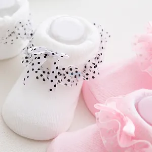 Detail of baby socks featuring delicate lace bows with polka dots and soft knit texture