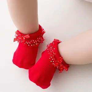 Close-up of red cotton baby socks with white polka dot lace ruffles and bow details