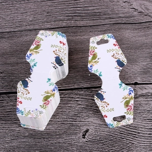 Macro shot of paper earring display cards featuring watercolor floral and bird patterns