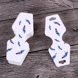 Detailed view of white jewelry display cards with elegant feather patterns on wood