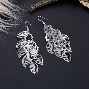 Macro shot of silver layered hollow leaf drop earrings on dark textured background