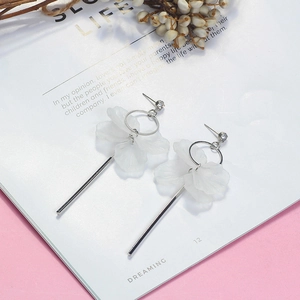 Vue rapprochée de boucles d'oreilles pétales blancs avec détails argentés sur revue