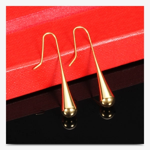 Close-up of golden teardrop earrings on red jewelry box with elegant reflection