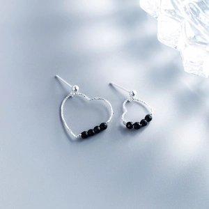 Close-up of silver heart stud earrings with black beads and spherical screw backs