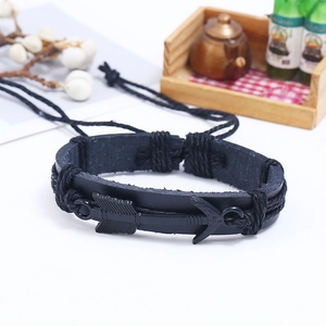 Detail of woven black leather bracelet with metal arrow and anchor charms on white background