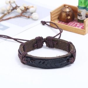 Detail of vintage braided leather bracelet with a black alloy feather charm and beads