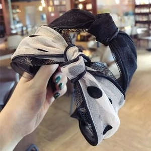 Close-up of black mesh headband featuring a stylish black and white polka dot bow detail