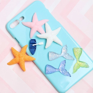 Detail of colorful resin starfish and mermaid tails accessories for DIY phone cases