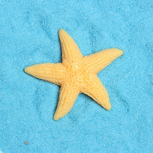 Macro shot of yellow resin starfish with realistic texture on blue sand background
