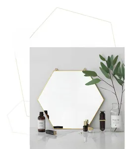 Detalle de un espejo de pared hexagonal de latón dorado con marco de metal nórdico moderno