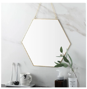 Close-up of golden hexagonal mirror with hanging chain on marble wall