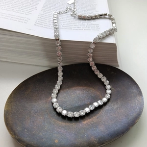 Dettaglio ravvicinato di una collana tennis argento con zirconi su un vassoio vintage