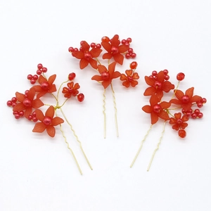 Detailed view of red resin flowers and beads on golden bridal hair pins set of three
