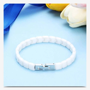 Detail of white ceramic chain bracelet with metal clasp and floral background