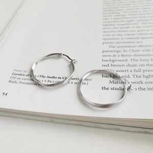 Macro detail of silver Mobius stud earrings with matte texture on an art book page