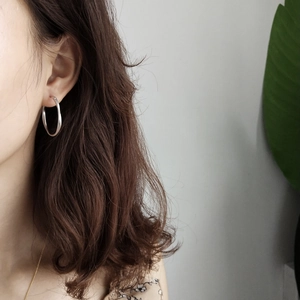 Close-up of matte silver Mobius earrings worn by model with minimalist styling