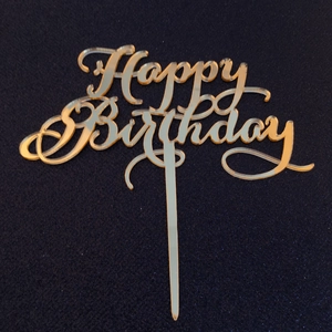 Macro shot of gold mirror acrylic Happy Birthday cake topper with elegant cursive font