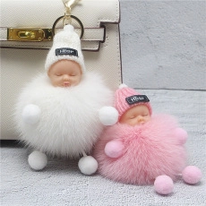 Close-up of fluffy mink fur ball keychains on a beige handbag with grey textured background