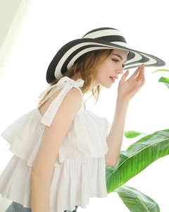 Side view of a woman wearing a wide brim sun hat with classic black and white stripes
