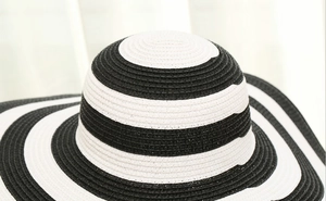 Detailed view of large brim straw hat featuring black and white woven circular stripes