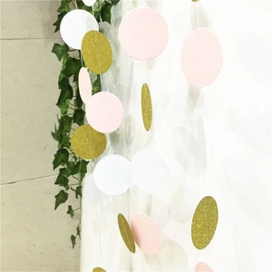 Close-up of pink, white, and gold glitter paper circle garlands hanging on a wall