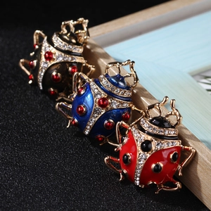 Macro shot of colorful enamel ladybug brooches with sparkling crystals on black surface