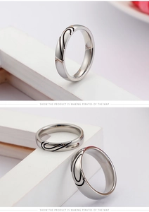 Detail of silver heart-shaped couple rings with abstract black line engraving