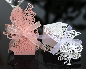 Detailed laser-cut hollow pink and white wedding favor boxes with angel design and ribbons