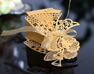 Detailed view of laser-cut gold angel candy box with ribbon and reflective surface