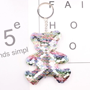 Close-up of colorful sequin bear keychain with metal ring on minimalist background