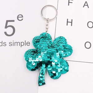 Close-up of a green sequins clover keychain with silver metal ring on white card